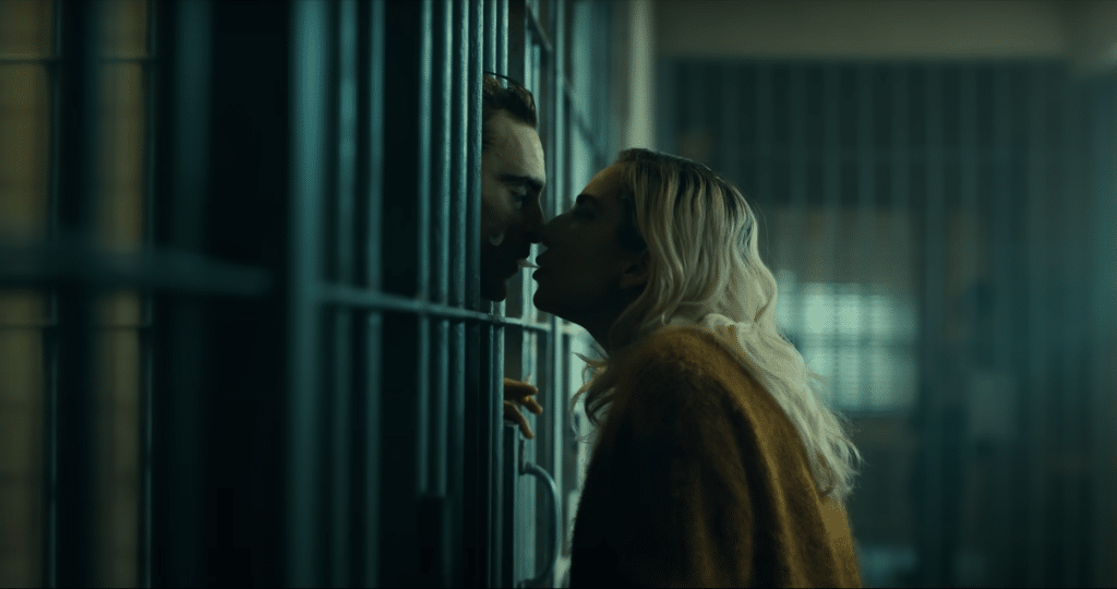 A screenshot of the trailer for "Joker: Folie À Deux" showing Arthur Fleck and Harley Quin exchanging a kiss through a jail cell.