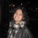 A girl with a scarf smiling.