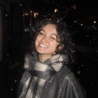 A girl with a scarf smiling.