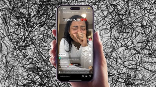 A hand is holding an iphone that is playing a TikTok video of a creator crying at the results of the 2024 election.