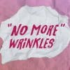 An image with skincare products laid out on a table. In the middle is a piece of paper that reads "No more wrinkles"