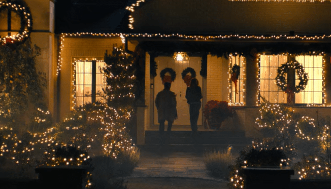 A man and woman walk up the stairs to the front door of a very decorated house.