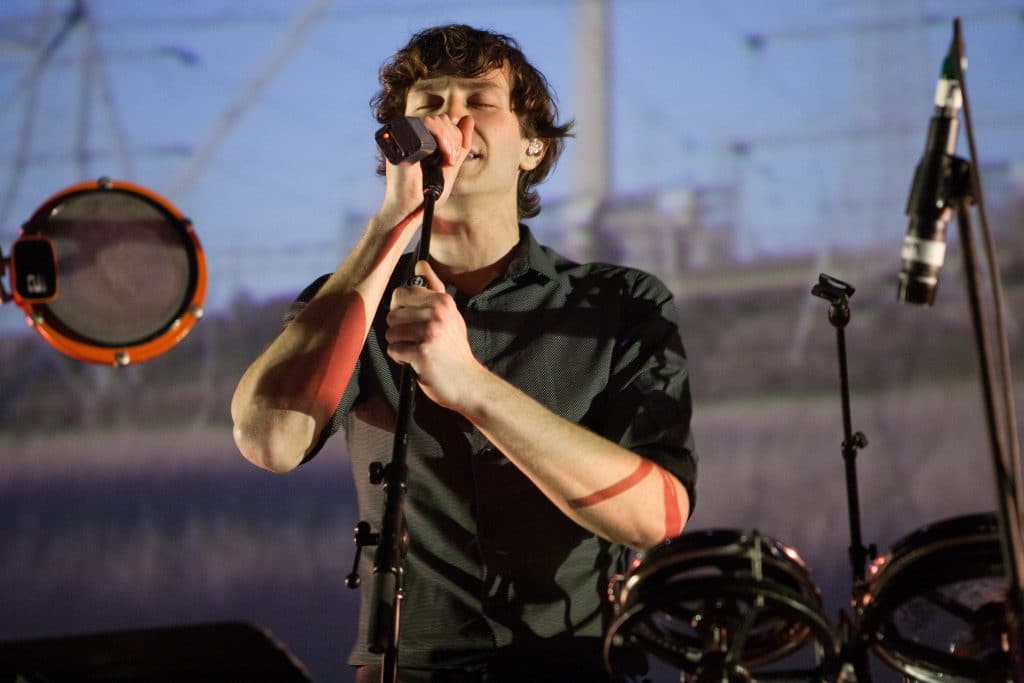 Gotye performing on stage in all black.