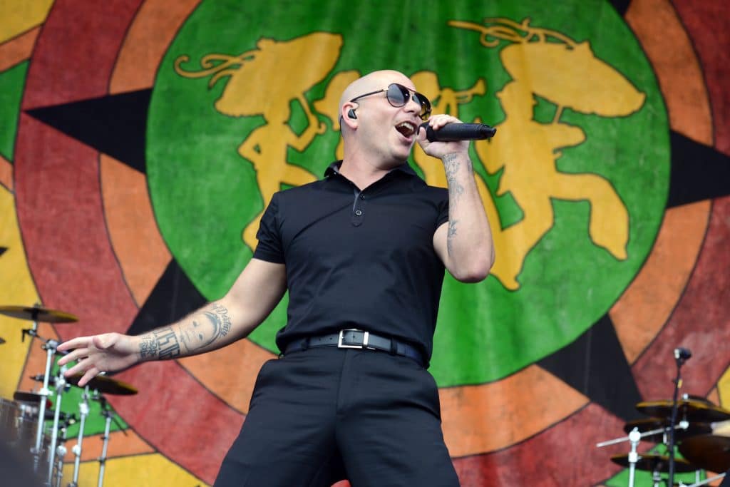 Pitbull performing on stage in all black.