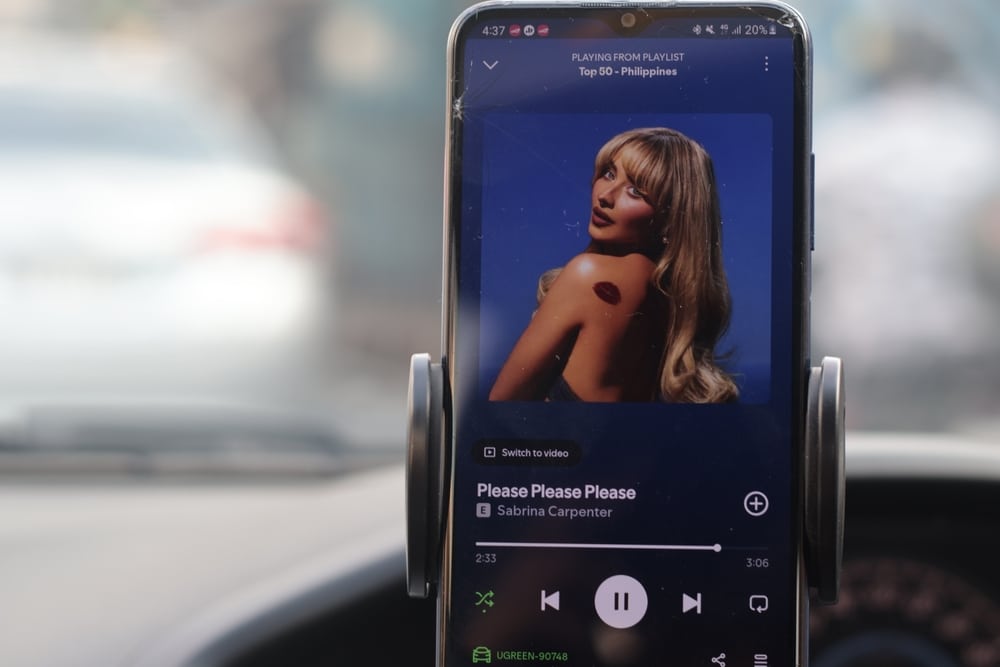 A phone that shows Sabrina Carpenter's "Please, please, please" on Spotify