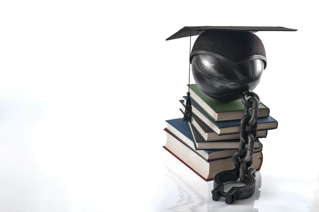 ooks with a chain and graduation cap represents the pressures of being a first-generation college student.
