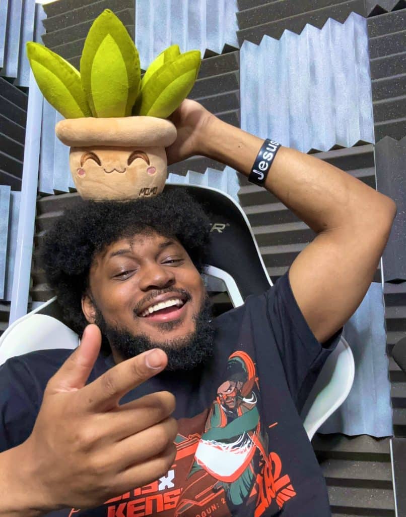 Coryxkenshin returns in 2025 to making Youtube videos. He is grinning and posing with a potted plant plush on his head.