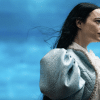 Bella Baxter (Emma Stone) stares off to the right in front of a blue sky