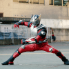 Kamen Rider Ryuki takes a fighting stance in a concrete lot.
