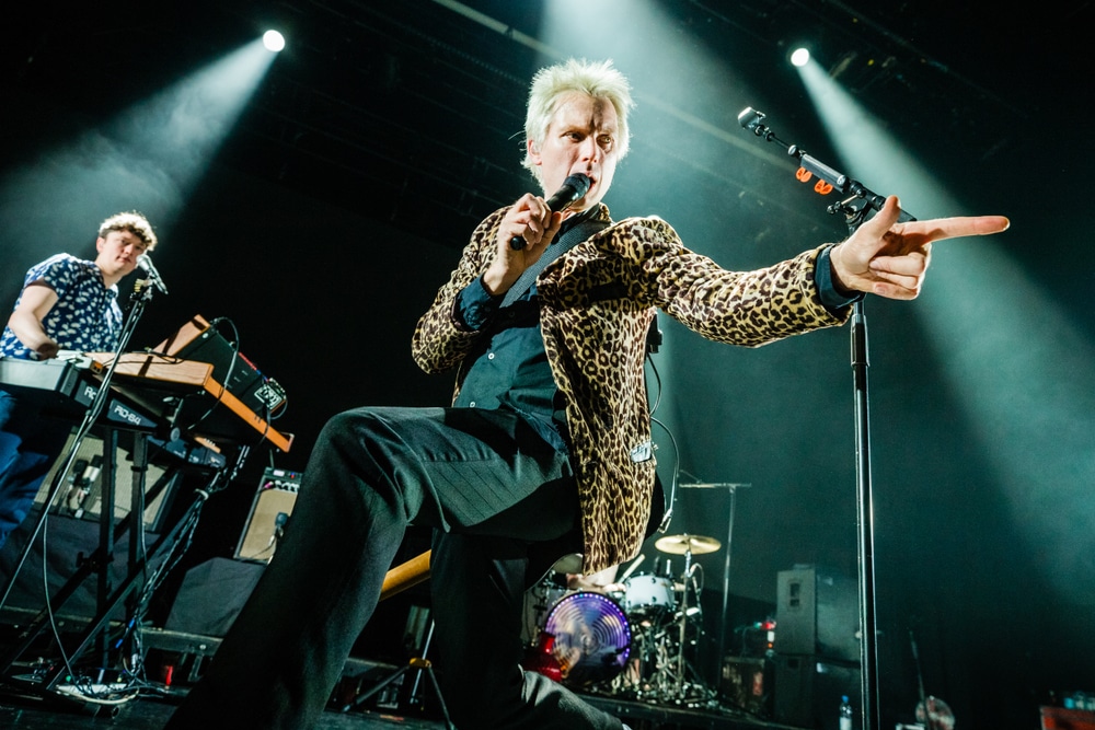 Front man Alex Kapranos pointing to the crowd whilst performing on stage.