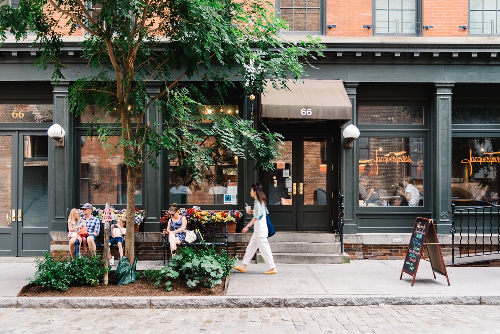 Classic NYC street with shops and people sitting and walking by