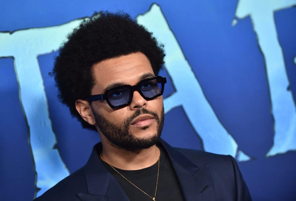 The Weeknd pictured at a press event wearing a suit blazer and sunglasses