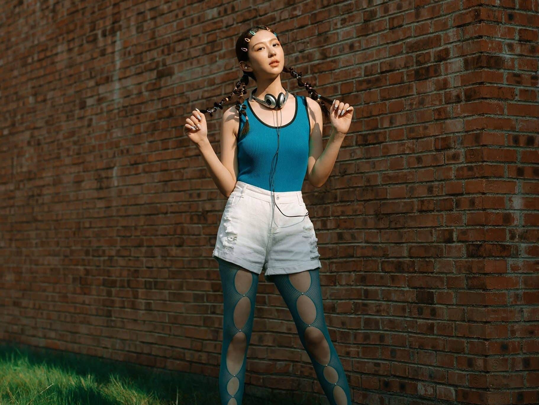 stylish young woman standing in front of brick wall