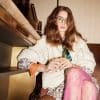 stylish woman in bold outfit sat in chair legs crossed