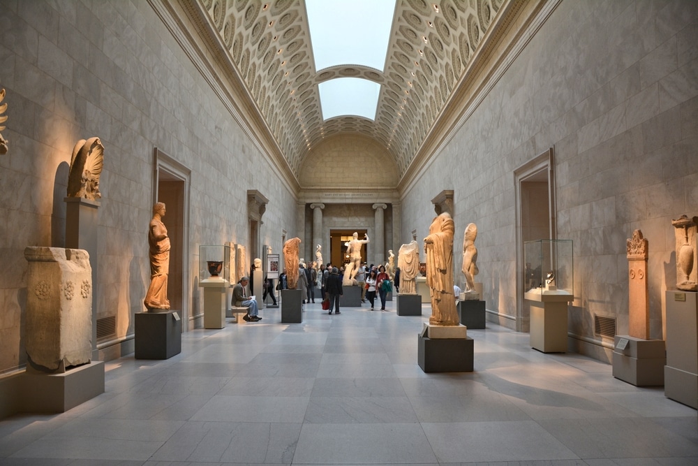 The MET museum room with marbled walls and statues with spotlight lighting