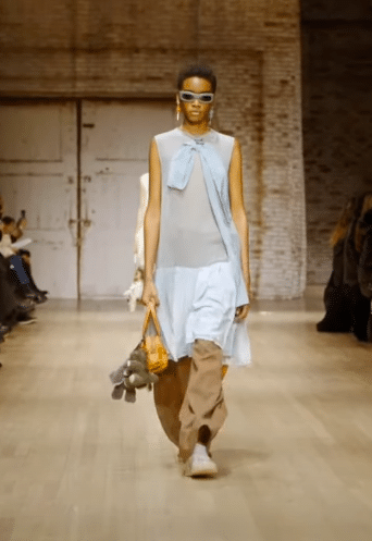 A model wearing a baby blue slip dress over tan trousers at the Coach fall/winter 2025 New York Fashion Week show.