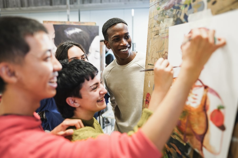 Multiracial students painting inside art room, class at university