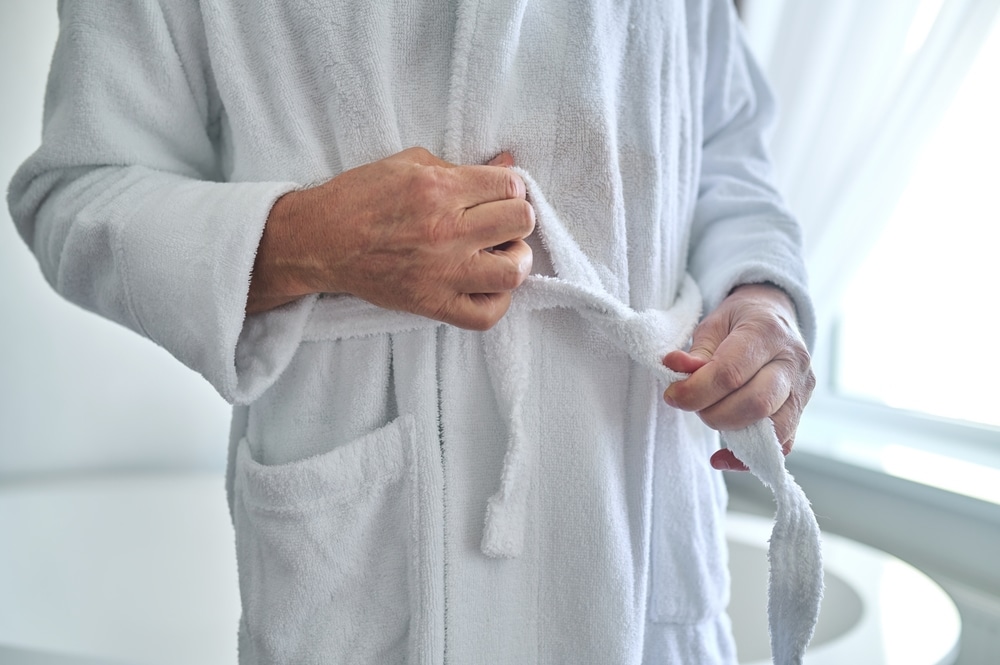 Torso angle of man tying on a white robe