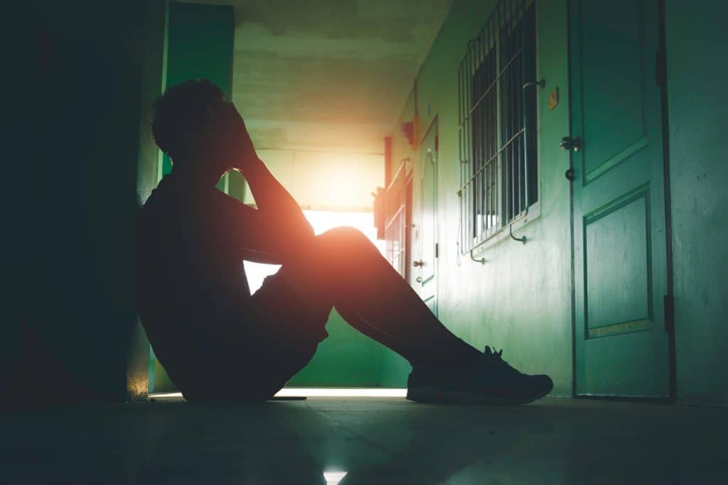 Someone sitting curled on floor feeling unlovable