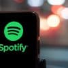 Phone with Spotify logo in front of city background.