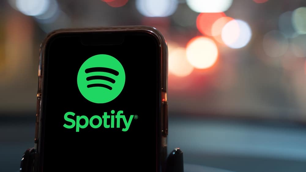 Phone with Spotify logo in front of city background.