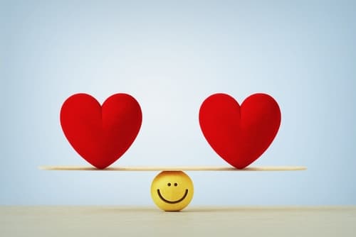 Two hearts balanced equally on a ball with a smiley face.
