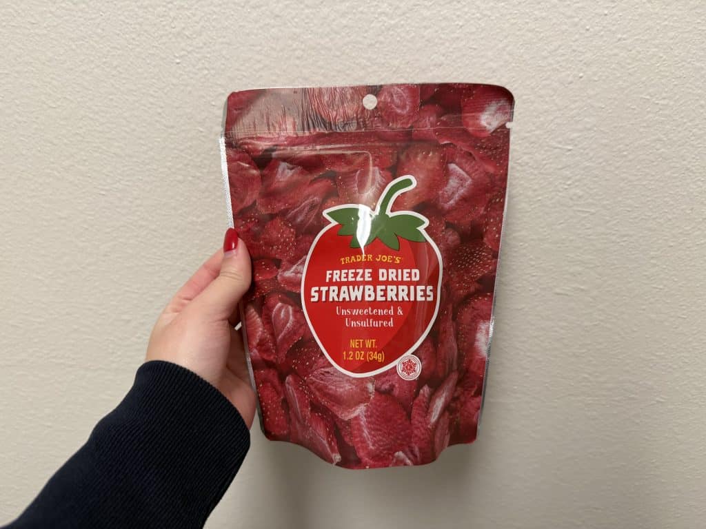 A package of freeze dried strawberries with a large strawberry in the center middle, in front of a white wall background