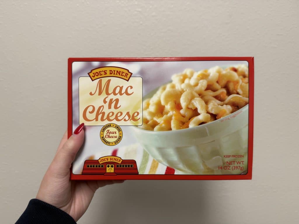 A rectangular box of frozen mac & cheese in front of a white wall background.