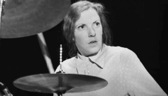 Black-and-white of Tucker as she performs behind a drum.