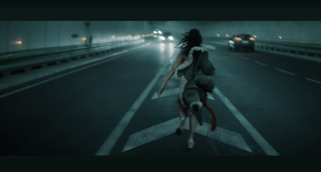 A screenshot of FKA Twigs running through a tunnel in the "Striptease" music video.