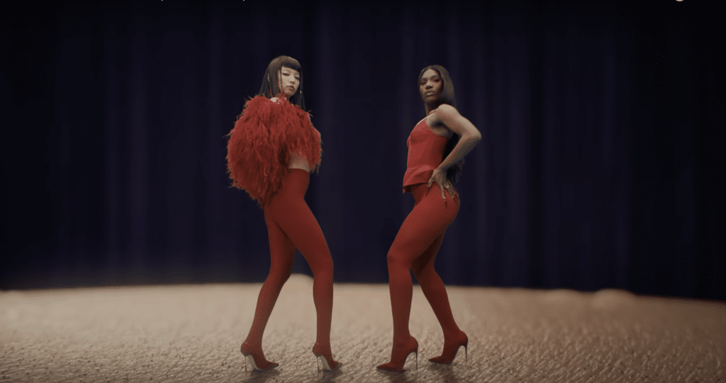 A screenshot of Doechii and JENNIE atop a man's head in the "ExtraL" music video.