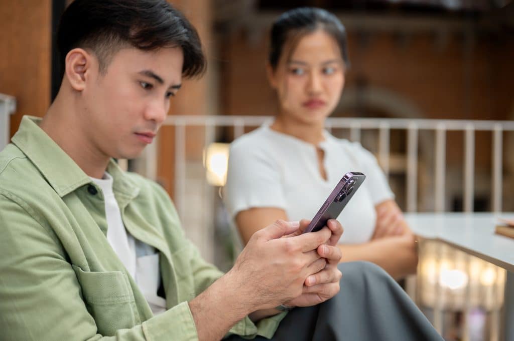 Girl annoyed at her friend who is pahying more attention to his phone than her.