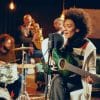 Female musician singing and playing green guitar.