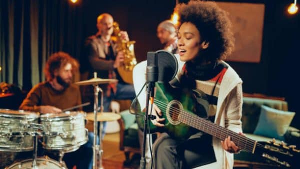 Female musician singing and playing green guitar.
