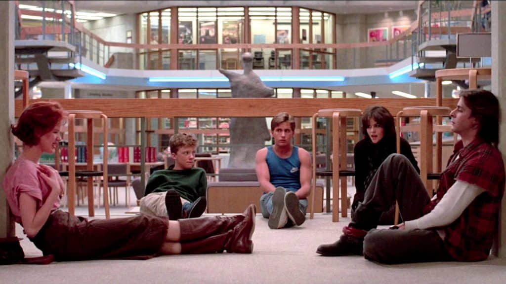 A group of students sits on the floor in a library where their detention takes place.