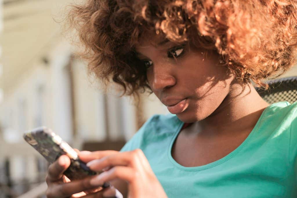 Woman looking down at her phone she's holding at her chest with both hands