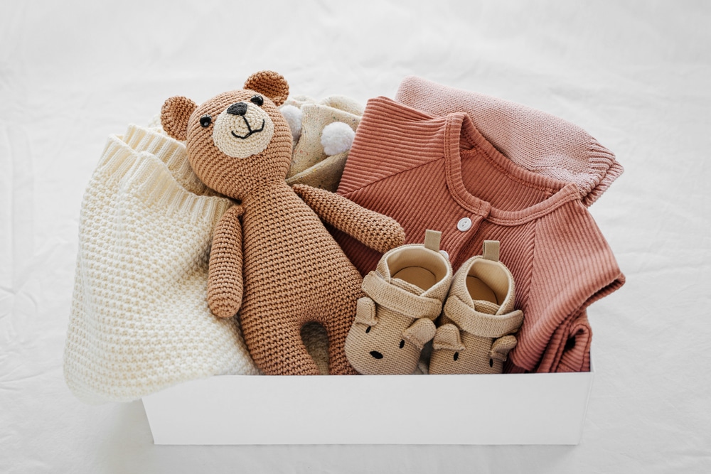 White gift box with baby clothes and toy bear