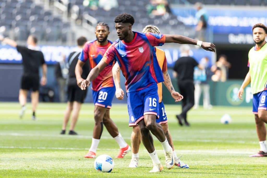 Image of Patrick Agyemang about to kick football on the pitch. He has three other players behind him.