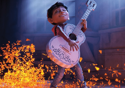 Miguel playing the guitar surrounded by glowing orange marigold petals in Coco. (Credit: Disney/Pixar)