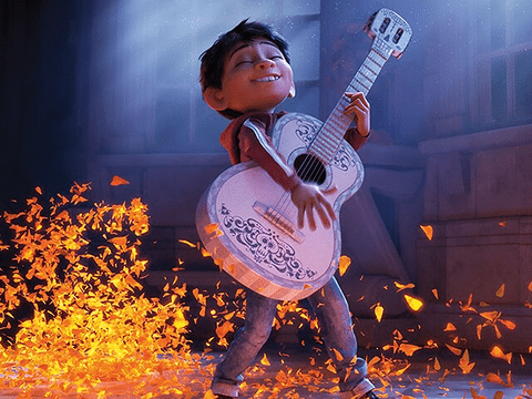 Miguel playing the guitar surrounded by glowing orange marigold petals in Coco. (Credit: Disney/Pixar)