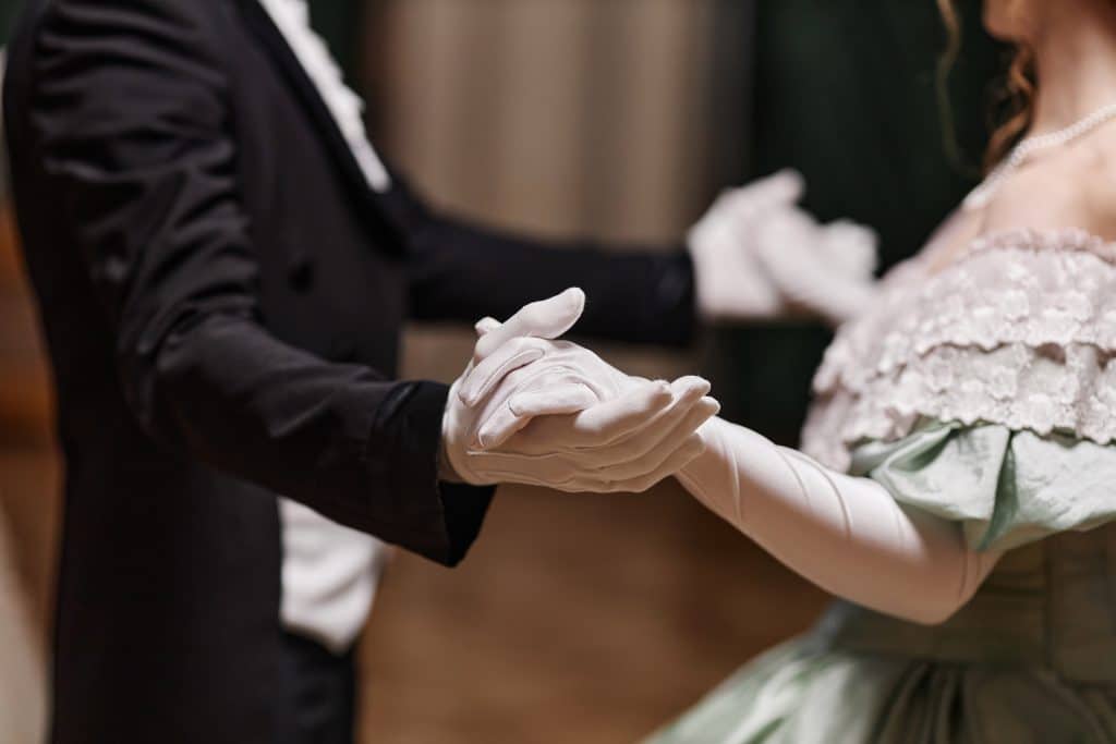 A man and woman dressed in Regency-era clothing dancing together at a ball.