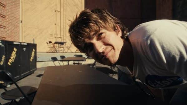 Keery leans over a table.