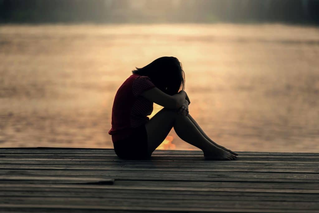 a girl holding her knees to her chest sad