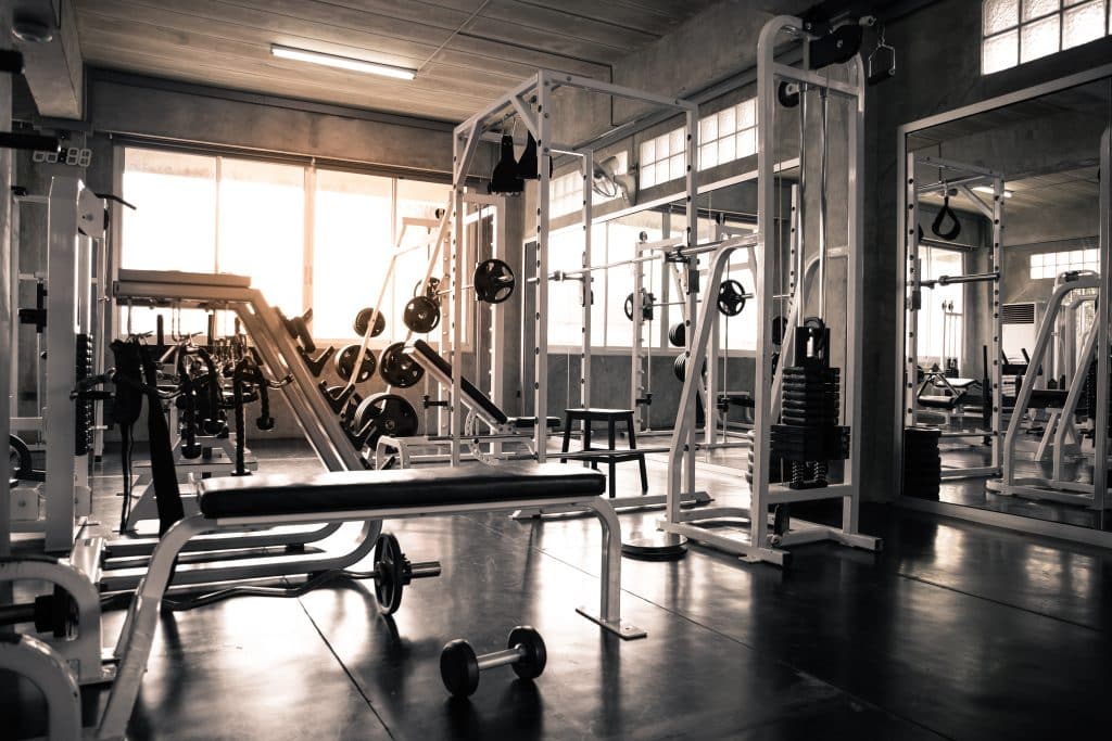 Image shows an empty gym, with various workout machines and equipment, such as weights and barbells.