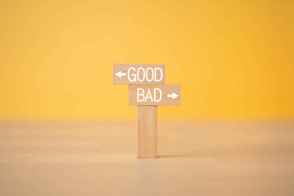 Wooden block sign with two opposing arrows that say good and bad
