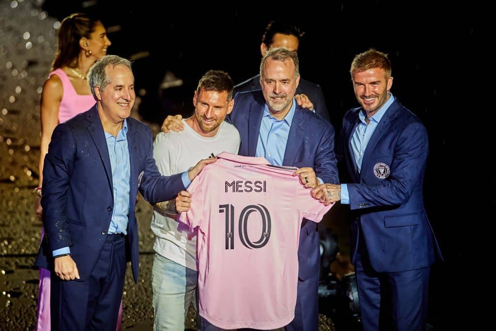 David Beckham poses with owners of Inter Miami FC and Lionel Messi, all holding a pink jersey that reads Messi 10.