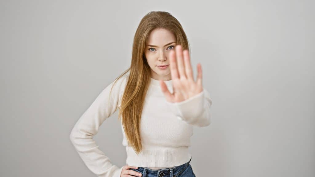 Image shows young woman holding her hand up, in a "stop" motion.