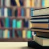 Image of books stacked on top of one another in a library setting.