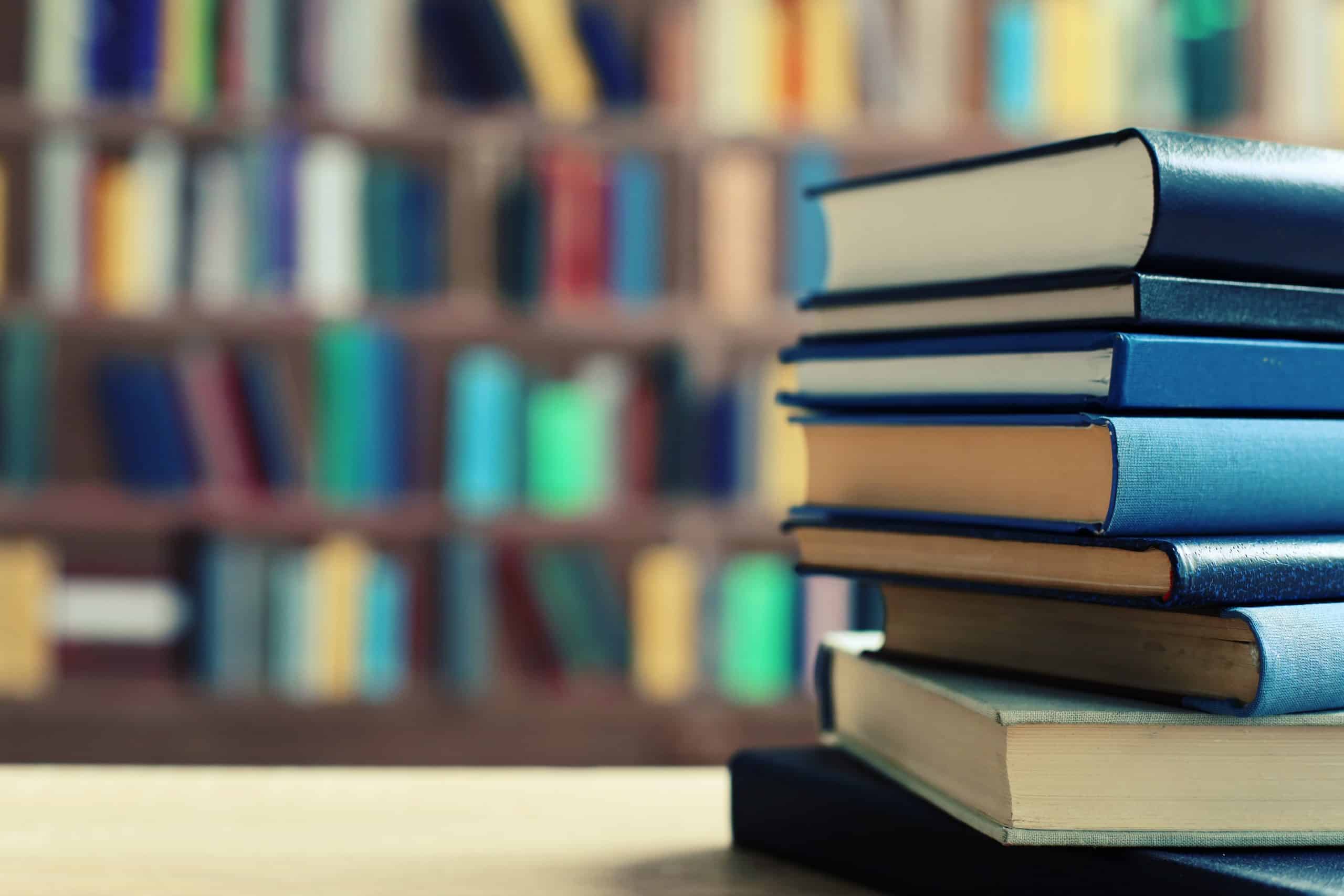 Image of books stacked on top of one another in a library setting.