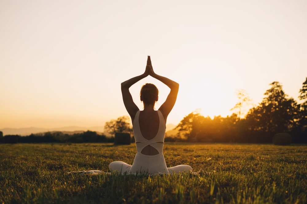 young woman practicing yoga as the sun rises